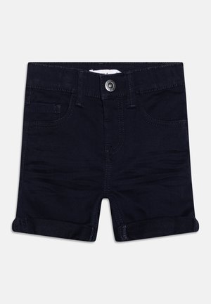 Mørkeblå denimshorts med opsmøgede kanter, knap foran, bæltestropper og for- og møntlommer, lagt fladt på en hvid baggrund.