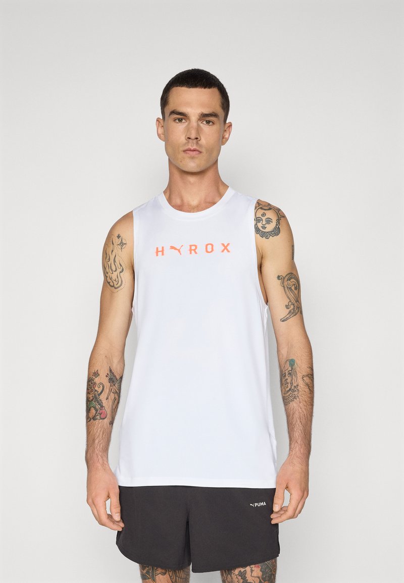 White sleeveless athletic tank top featuring orange "HYROX" logo on chest. Smooth fabric, round neckline, paired with black shorts.