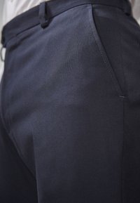 Marineblaues Hosen aus glattem Stoff mit taillierter Passform, ausgestattet mit einer Seitentasche und dezenten Nähten.