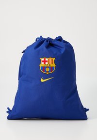 Sac à cordon bleu en tissu, orné du blason du FC Barcelone et d'un logo Nike jaune, avec une surface texturée et un haut froncé.