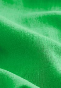 Tissu vert éclatant avec une surface lisse et légèrement texturée, présentant un motif de tissage homogène et une couleur vive.