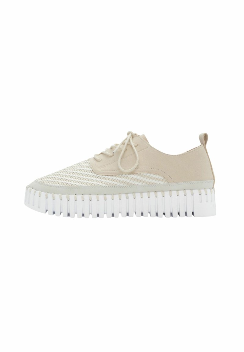 Zapatilla beige con parte superior de malla y ante, puntera redondeada, suela blanca estriada y cordones en la parte delantera. Presenta una pestaña en bucle en la parte trasera.