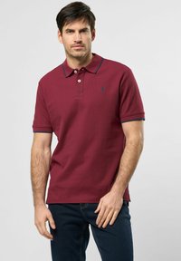 Burgundská polo košile s vroubkovanou texturou, zapínáním na dva knoflíky a kontrastním námořnickým lemováním na límci a rukávech. Malé logo na hrudi.