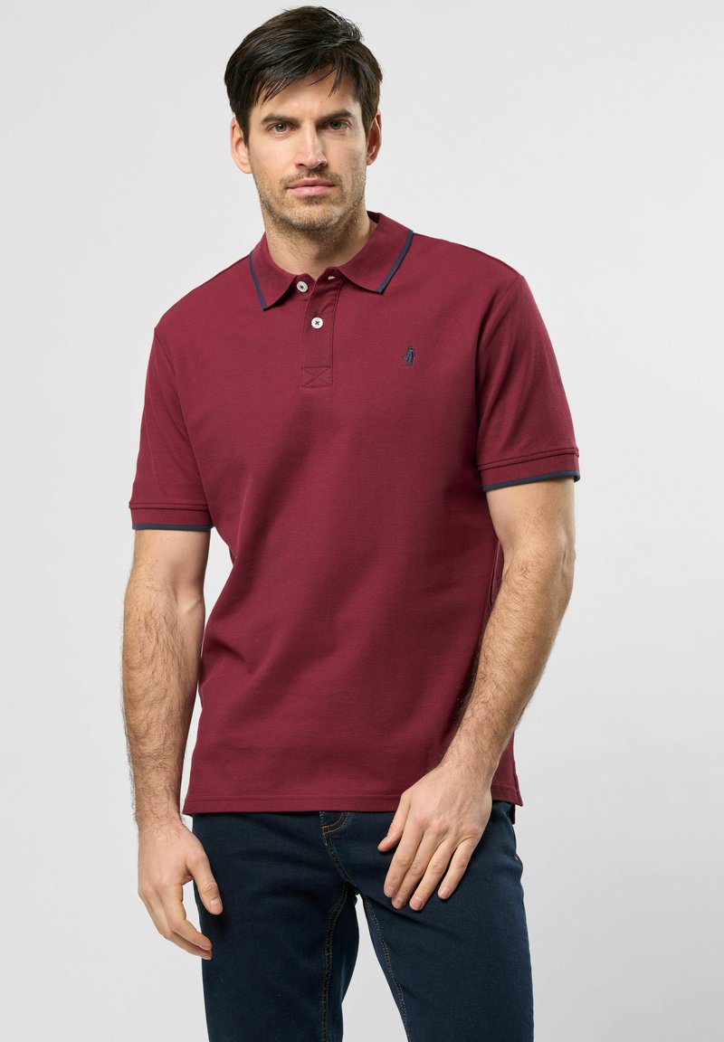 Burgundská polo košile s vroubkovanou texturou, zapínáním na dva knoflíky a kontrastním námořnickým lemováním na límci a rukávech. Malé logo na hrudi.