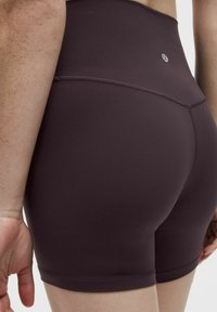 Pantalones cortos de talle alto en color malva oscuro con una textura suave, que presentan detalles de doble costura y un logo en la cintura.