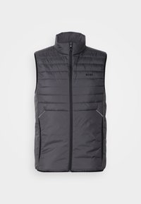 Grå vadderad väst med hög krage, frontdragkedja, sidofickor och subtil logotyp på bröstet; elegant och lätt design.