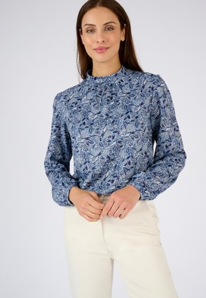 Blusa azul con estampado, cuello alto, mangas largas y detalles fruncidos en los hombros. El material parece ligero y presenta motivos florales.