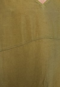 Olivgrünes Kleidungsstück mit V-Ausschnitt, das eine glatte Textur und eine horizontale Nahtdetails in der Mitte aufweist.