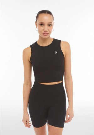 Ensemble de vêtements de sport noir composé d'un crop top sans manches et de shorts taille haute. Fabriqué à partir d'un matériau lisse et extensible avec un accent de logo.