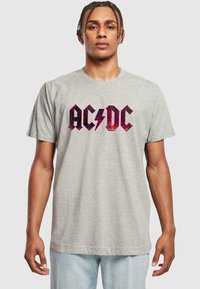 Pelēka kokvilnas t-krekls ar izteiksmīgu sarkanu un melnu "AC/DC" grafiku ar zibens bultu. Īsas piedurknes, apaļa kakla izgriezuma, brīvs piegriezums.