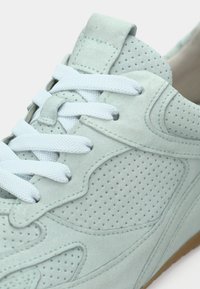 Αθλητικό παπούτσι από σουέντ σε ανοιχτό πράσινο μέντας με διάτρητο σχέδιο, λευκά κορδόνια και λαστιχένια σόλα σε ανοιχτό καφέ χρώμα. Διαθέτει ραφές και επενδυμένο περιλαίμιο.