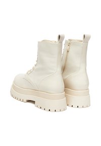 Masywne botki za kostkę w off-white skórze z okrągłym noskiem, sznurowaniem z przodu i zamkiem błyskawicznym z boku. Gruba platforma z teksturowaną podeszwą.