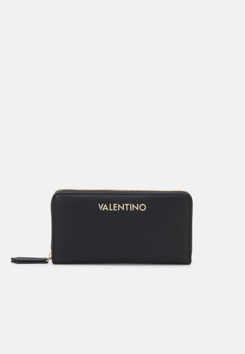 Juodas odinis pinigine su auksiniu "VALENTINO" logotipu. Turi užtrauktuko uždarymą ir tekstūruotą paviršių. Kompaktiška stačiakampio forma.