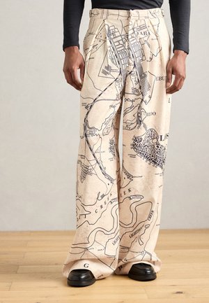 Beige wide-leg trousers featuring a black map design with notable geographical details. Constructed from a soft, textured fabric.
