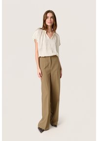 Blusa a righe crema con scollo a V e maniche corte abbinata a pantaloni beige a vita alta e a gamba larga. Le calzature presentano un accento decorativo.