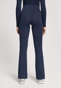 Pantaloni flared a vita alta di colore blu navy realizzati in un tessuto elasticizzato, caratterizzati da una texture morbida e un design semplice e pulito.