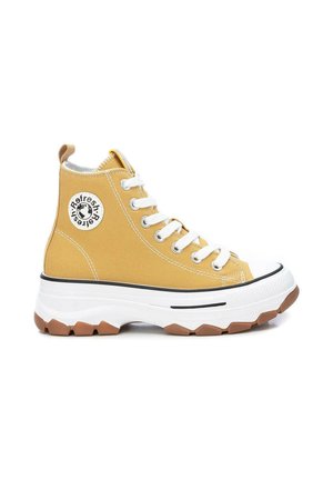Zapatilla amarilla de lona de caña alta con cordones blancos, suela blanca gruesa, dibujo marrón y parche redondo con logo en el lateral.