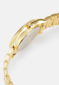 Gouden polshorloge met een ronde kast, een strakke lunette en een geschakelde metalen armband. Beschikt over een helder glas en een minimalistisch ontwerp.
