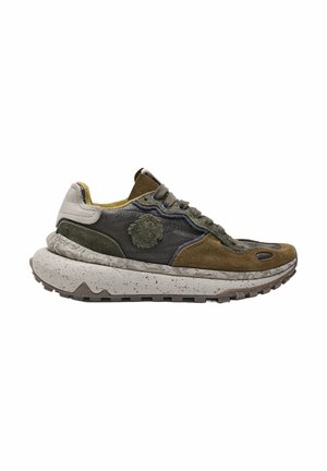 Zapatilla baja con paneles superpuestos de cuero y ante marrón, verde y gris, suela gruesa moteada y parche circular texturizado en el lateral.