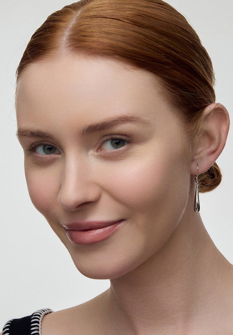 Srebrne kolczyki w kształcie kropli z wypolerowanym wykończeniem, zawieszone na cienkim haczyku. Gładka tekstura i wydłużony kształt podkreślają ich elegancję.