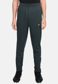 Dunkelgraue Sporthose mit elastischem Bund und gelbem Nike-Logo auf der linken Seite, gefertigt aus glattem, leichtem Stoff.