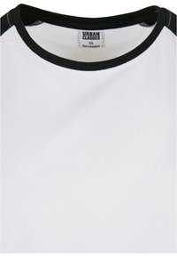Valkoinen t-paita pyöreällä kauluksella, jossa on musta ribbireunus. Pehmeä rakenne, siisti muotoilu ja Urban Classics -labeli kauluksessa.