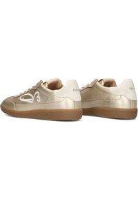 Sneakers in pelle dorata con un accento bianco, caratterizzati da un design testurizzato, lacci piatti e suola in gomma marrone, con marca sul tallone.