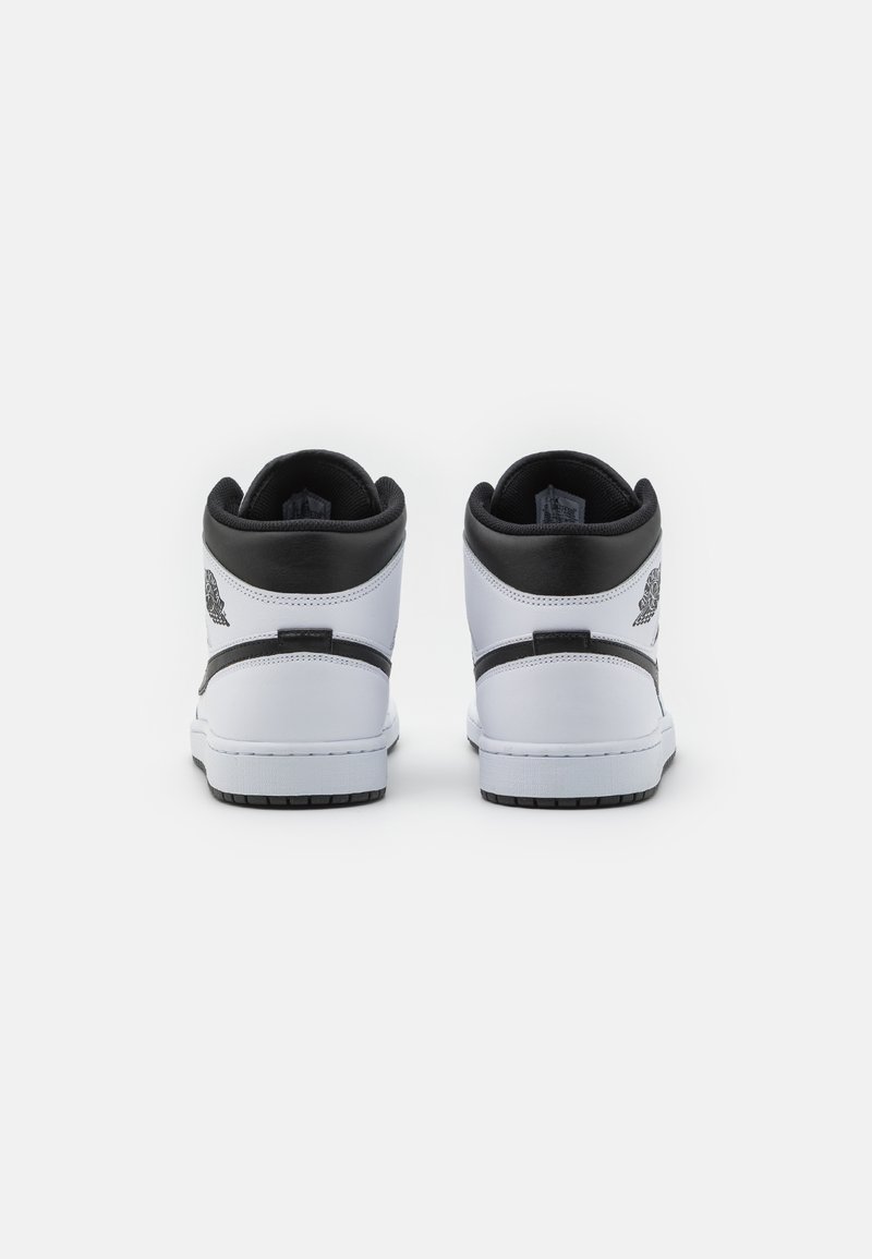 Zapatillas altas de cuero blanco, con acentos en negro, textura suave y puntera redonda. Presenta un logo en la parte trasera y una suela de goma.