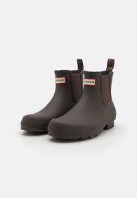 Ruske rubber ankle boots with elastic side panels ja pull tab. Contains valkoinen ja punainen "HUNTER" logo edessä. Teksturoitu pohja pidon takaamiseksi.