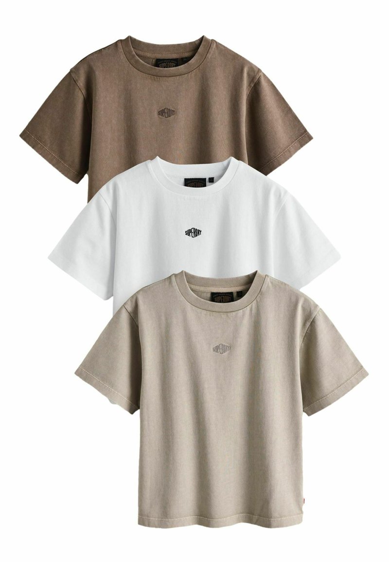 Tres camisetas de manga corta exhibidas: una marrón, una blanca y una beige. Cada una tiene cuello redondo y un pequeño logo en el pecho.