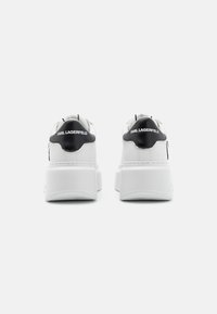 Vita sneakers med en svart hälaccent, slätt lädermaterial och en tjock plattformsåle. "KARL LAGERFELD"-logotyp på hälen.