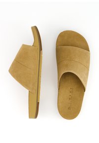 Sandales à glissière en suède beige comportant un design à large bande, un dessus texturé, une semelle intérieure rembourrée et une semelle externe en caoutchouc durable avec adhérence.