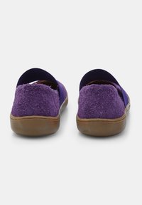 Zapatillas moradas sin cordones con una parte trasera texturizada y peluda y una suela de goma plana de color marrón claro. Diseño de abertura trasera. Tela morada suave en la parte delantera.