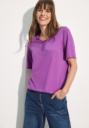 Paarse T-shirt met korte mouwen, voorzien van een V-hals ontwerp, zachte stof en een ruime pasvorm, gecombineerd met blauwe spijkerbroek.