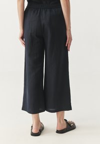 Marineblauwe wijde broek met een elastische tailleband, gemaakt van lichtgewicht stof, met een gladde textuur en een cropped lengte.