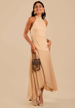 Nude halter dress with layered, flowing skirt; paired with a sparkly gold bag and silver platform heels. Smooth texture and elegant silhouette.