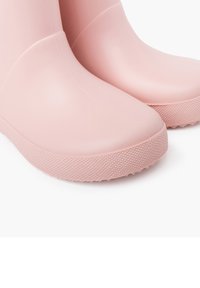 Bottes de pluie en caoutchouc rose avec une finition lisse, bout arrondi, semelle texturée et un design sans couture.