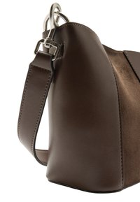 Brązowa torebka o gładkiej skórzanej fakturze, z miękkim zamszowym panelem, regulowanym paskiem i srebrnym metalowym akcentem.