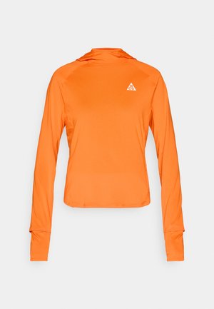 Sportovní tričko s dlouhým rukávem v jasně oranžové barvě, vyrobené z lehké, hladké látky. Má design na přetažení přes hlavu s trojúhelníkovým logem jako detailem.