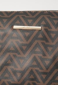 Brun och svarttexturerad konstläderhandväska med ett geometriskt mönster, med en hardware-accent i guldton som har varumärket "ALDO."