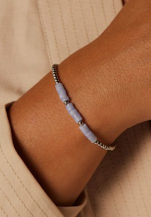 Kralenarmband met zilverkleurige metalen kralen afgewisseld met lichtpaarse rubberachtige schijven, ontworpen om strak om de pols te passen.