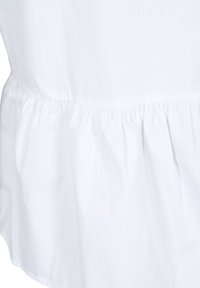 Blusa di tessuto bianco con orlo peplum, texture liscia e arricciature in vita per un ulteriore dettaglio di design.