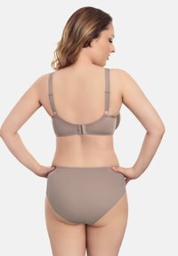Sujetador beige y bragas a juego de talle alto hechas de tela suave. El sujetador cuenta con tirantes ajustables y un cierre de gancho y ojo en la parte trasera.