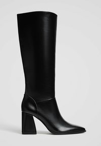 Botte en cuir noir arrivant aux genoux avec un bout pointu, un talon épais, une texture lisse et un design sans coutures. Convient à diverses occasions.