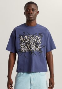 Kurzärmliges T-Shirt aus Baumwolle in Marineblau mit einem gewagten, abstrakten, mehrfarbigen Grafikdesign in der Mitte. Lockerer Schnitt und Rundhalsausschnitt.