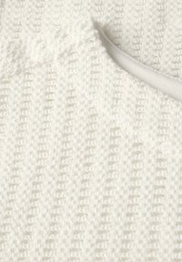 Tissu en tricot blanc avec un motif texturé et un col lisse. Le design présente des lignes verticales et une apparence douce et confortable.