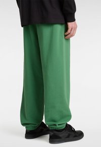 Groene sweatpants van zachte stof, met een elastische tailleband en boorden. Gecombineerd met zwarte sneakers voor een sportieve uitstraling.