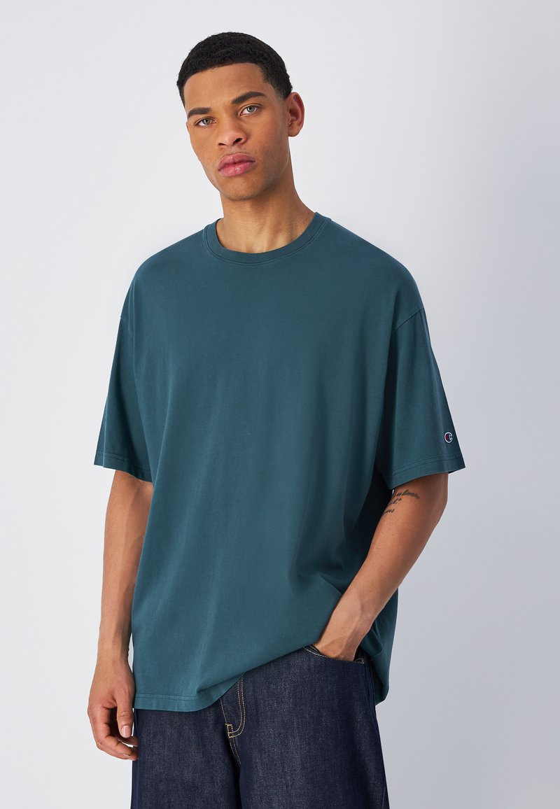 Turkusowa, oversize'owa koszulka z bawełny, z krótkimi rękawami i okrągłym dekoltem. Zawiera małe logo na lewym rękawie.