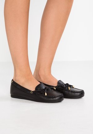 Zwarte leren mocassinschoenen met een gestructureerde afwerking, decoratieve strik en gouden hardwareaccenten. Laag profiel met een afgeronde teenvorm.