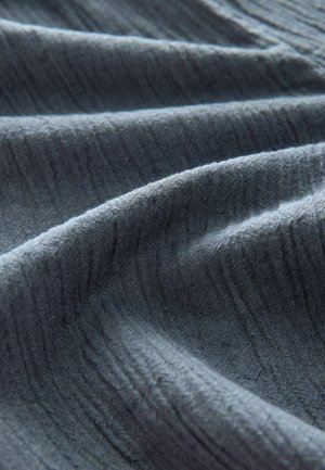 Mørkeblåt stof med en blød, struktureret overflade, der har fine lodrette linjer og blide folder. Velegnet til forskellige tekstilapplikationer.